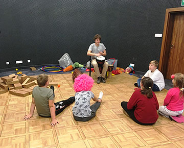 Fotografia przedstawia dzieci zgromadzone wokół mężczyzny, który gra na bębenku. Zdjęcie pochodzi z archiwum beneficjenta.