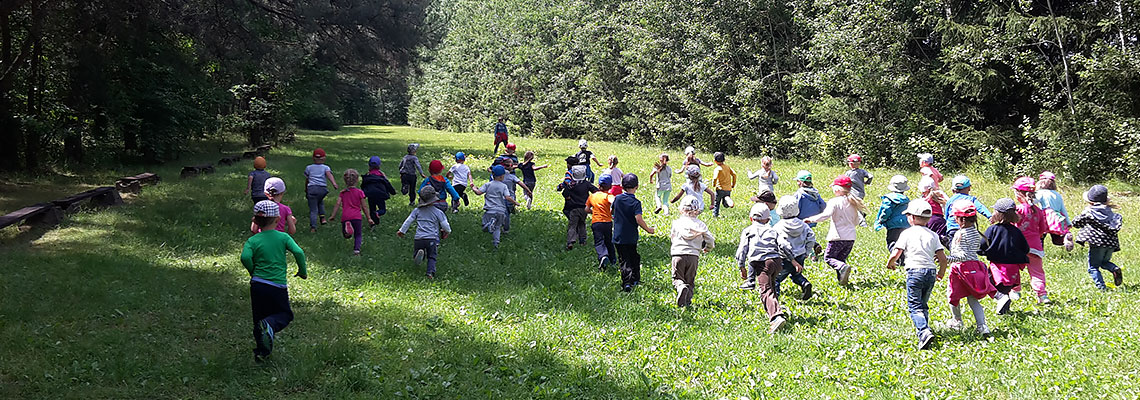 Fotografia przedstawia dzieci biegnące leśną polaną. Zdjęcie pochodzi z archiwum Nadleśnictwa Oborniki.