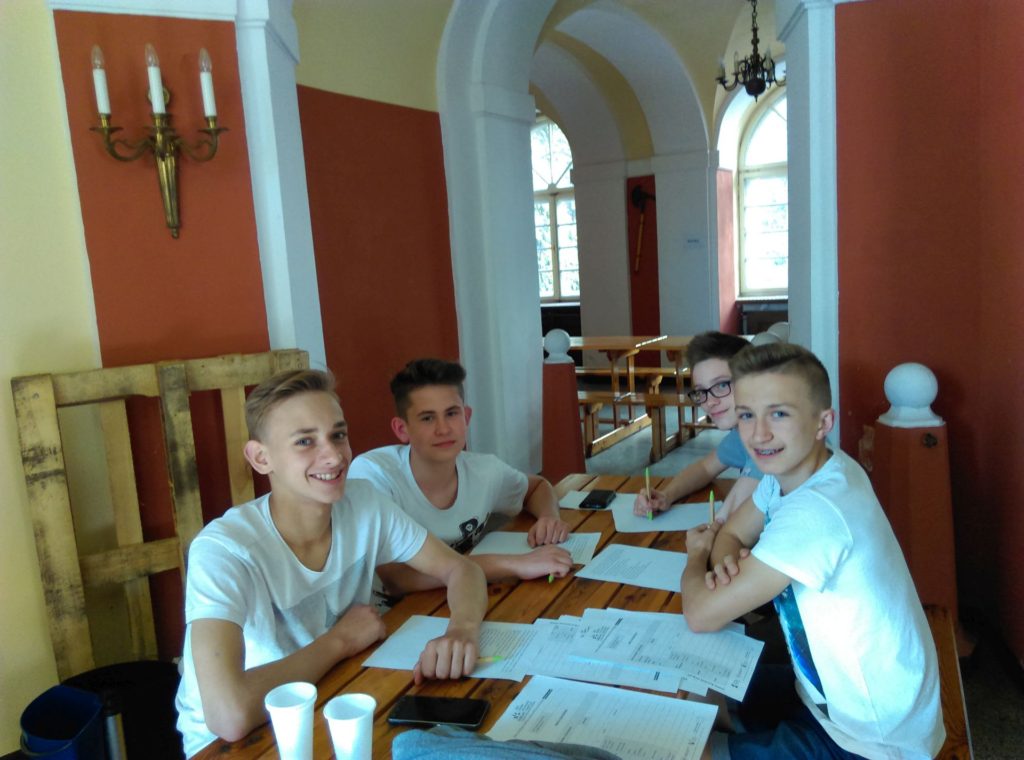 Czterech młodych chłopców siedzi przy stole podczas warsztatów 