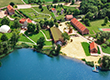 Zdjęcie przedstawia panoramę Skansenu Olenderskiego z widocznymi zabudowaniami folwarcznymi, jeziorem i osiemnastowiecznym młynem. Zdjęcie pochodzi z archiwum beneficjenta.