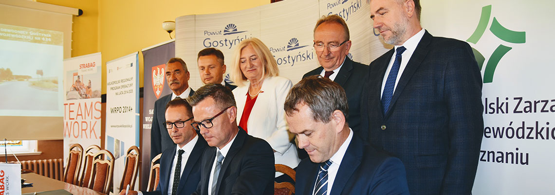 Fotografia przedstawia oficjeli podpisujących umowę. Zdjęcie pochodzi z archiwum Wielkopolskiego Zadządu Dróg Wojewódzkich.