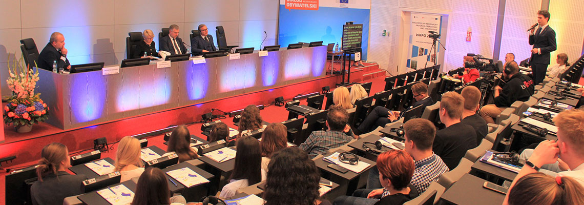 Fotografia przedstawia aulę, w której odbywa się debata. Widać debatujących oraz publiczność. Autorem zdjęcia jest Marcin Kryger.