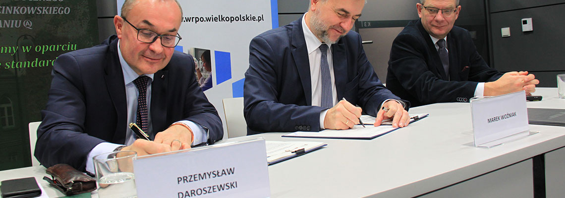 Fotografia przedstawia mężczyzn podpisujących umowę. Zdjęcie pochodzi z archiwum Urzędu Marszałkowskiego Województwa Wielkopolskiego.