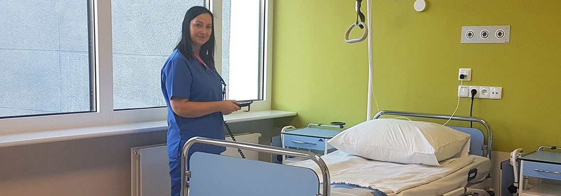Fotografia przedstawia pielęgniarkę obsługującą panel sterujący łóżka szpitalnego. Zdjęcie pochodzi z archiwum szpitala.