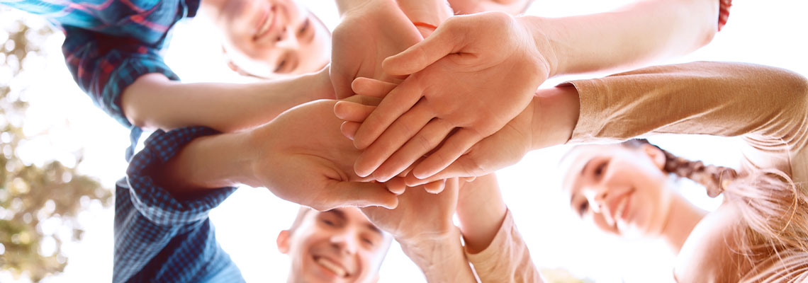 Fotografia przedstawia grupę osób nakładających dłonie jedna na drugą. Zdjęcie pochodzi z Obrazy licencjonowane przez Depositphotos.com/Drukarnia Chroma.