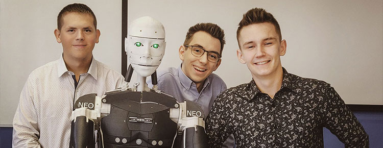 Fotografia przedstawia trzech uśmiechniętych chłopców pozujących do zdjęcia z robotem. Fotografia pochodzi z archiwum beneficjenta.