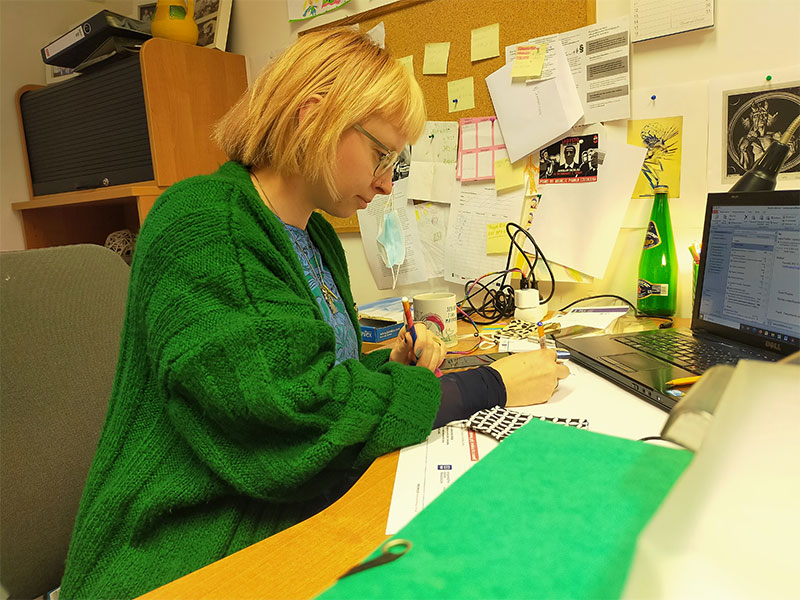 Fotografia przedstawia kobietę o prostych blond włosach, w okularach i zielonym swetrze, która w skupieniu pracuje przy komputerze. Zdjęcie pochodzi z archiwum prywatnego.