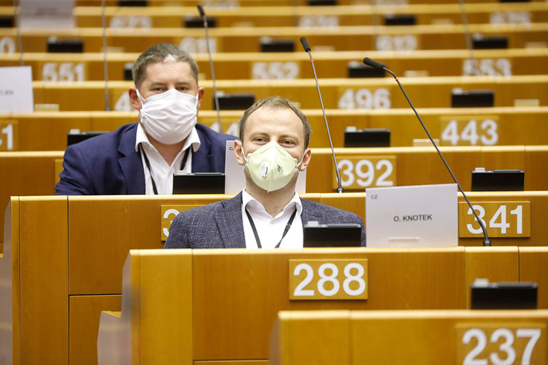 Fotografia przedstawia dwóch europarlamentarzystów w garniturach, w maseczkach ochronnych, na sali plenarnej. Autorką zdjęcia jest Thierry ROGE.