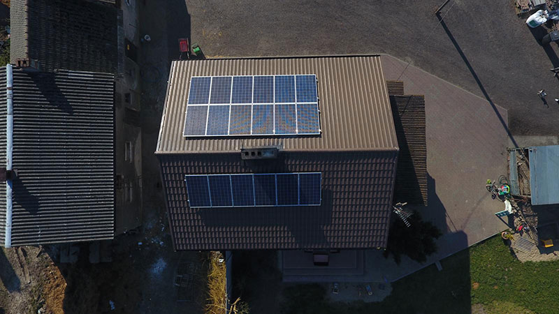 Fotografia wykonana z lotu ptaka pokazuje panele fotowoltaiczne zamontowane na skośnym dachu krytym dachówką jednego z domów. Zdjęcie pochodzi z archiwum Gminy Miasteczko Krajeńskie.