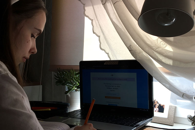 Fotografia przedstawia młodą uczennicę, rozwiązującą zadanie przy biurku. Na blacie stoi otwarty laptop. Zdjęcie pochodzi z archiwum prywatnego.