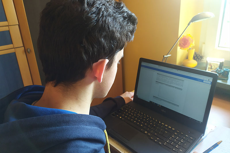 Fotografia przedstawia młodego ucznia czytającego zadanie na ekranie komputera, podczas lekcji online. Zdjęcie pochodzi z archiwum prywatnego.