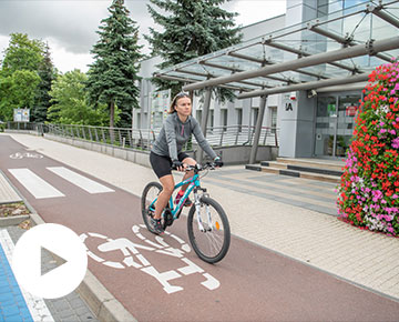 Fotografia przedstawia rowerzystkę ubraną w kolarski strój, która porusza się ścieżką rowerową. Autorem zdjęcia jest Maciej Motylewski.