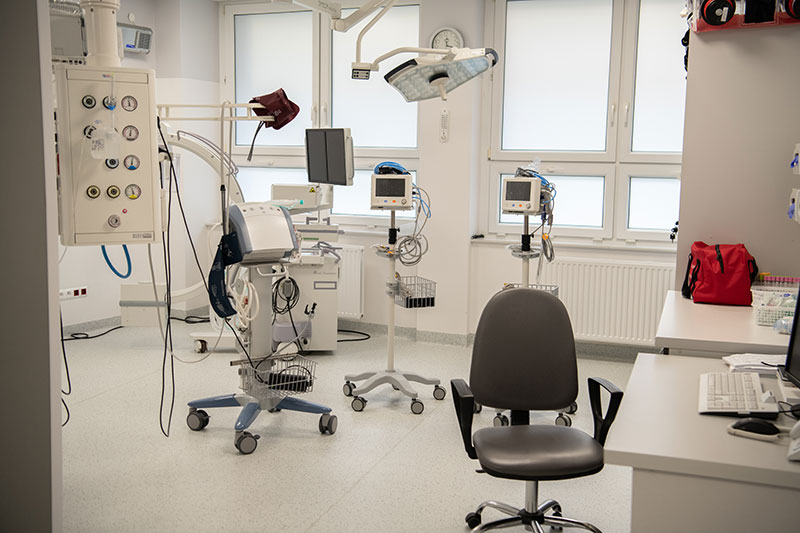 Fotografia przedstawia przenośny sprzęt szpitalny, składający się z rurek, kabli czy monitorów. Prawdopodobnie są to przenośne respiratory i kardiomonitory. Autorem zdjęcia jest Maciej Motylewski.