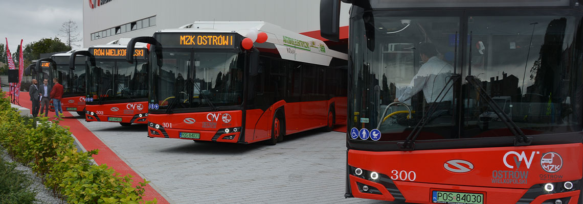 Fotografia przedstawia pięć nowych autobusów zaparkowanych na parkingu przed Areną Ostrów. Zdjęcie pochodzi z archiwum beneficjenta.