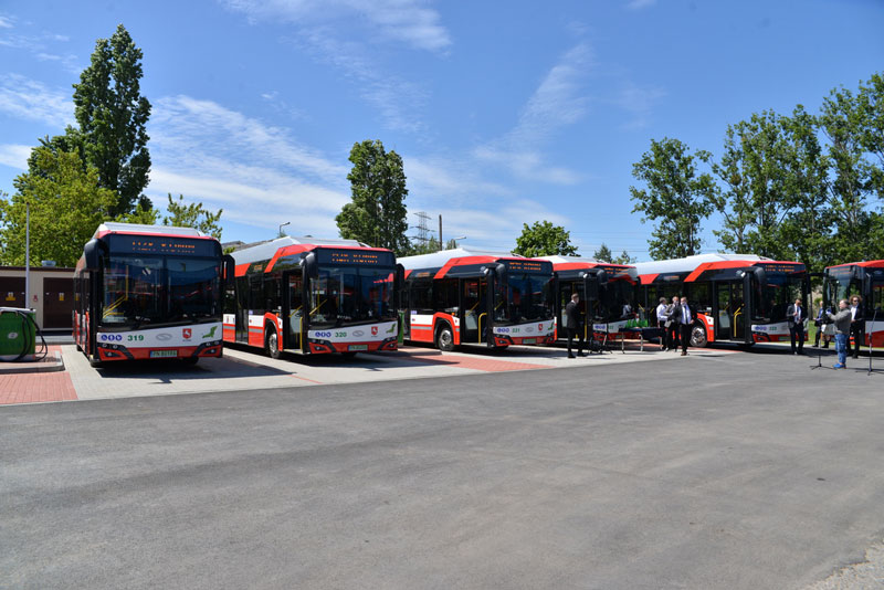 Fotografia przedstawia sześć nowoczesnych autobusów stojących w rzędzie, na zajezdni. Wokół widocznych jest kilka osób. Zdjęcie pochodzi z archiwum beneficjenta.