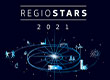 Grafika ma ciemne tło. Na górze jest napis REGIOSTARS 2021. Poniżej znajduje się jasna kula od której rozchodzą się promienie. Wokół niej, po orbicie zaznaczonej liniami, krążą różne symbole, między innymi rowerzysta, wiatrak, las czy most. W lewym dolnym rogu znajduje się napis #RegioStars, a poniżej link do strony internetowej www.regiostarsawards.eu. W prawym dolnym rogu jest logo Komisji Europejskiej oraz napis Regional and Urban Policy. Grafika pochodzi z archiwum Urzędu Marszałkowskiego Województwa Wielkopolskiego.