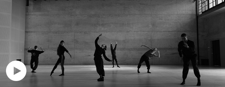 Czarno-biała fotografia przedstawia grupę sześciu tancerzy w różnych pozach, rozstawionych na parkiecie w przestronnej sali. Autorem zdjęcia jest Andrzej Grabowski.