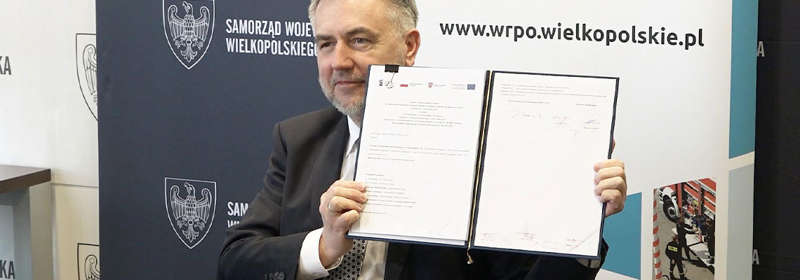 Fotografia przedstawia marszałka województwa wielkopolskiego Marka Woźniaka, który prezentuje podpisaną umowę na dofinansowanie. Zdjęcie pochodzi z archiwum Departamentu Polityki Regionalnej.