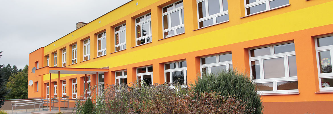 Fotografia przedstawia fasadę szkoły po termomodernizacji. Widoczna jest elewacja w pomarańczowo-czerwonych-żółych barwach. Zdjęcie pochodzi z archiwum beneficjenta.