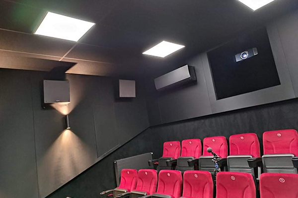 Fotografia przedstawia fragment sali w kinie społecznościowym. Widocznych jest kilka siedzeń z czerwonym oparciem i elementy nagłośnienia. Zdjęcie pochodzi z archiwum beneficjenta.