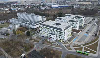 Fotografia z lotu ptaka przedstawia nowoczesny, sporych rozmiarów budynek szpitala. Autorem zdjęcia jest Maciej Motylewski.