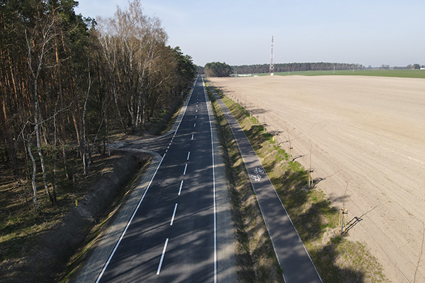 Fotografia przedstawia fragment nowo wybudowanej drogi. Poza jezdnią, po prawej stronie widać nową ścieżkę rowerową. Zdjęcie pochodzi z archiwum beneficjenta.