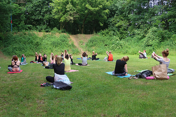 Fotografia przedstawia grupę osób, które praktykują jogę. Specjalne maty rozłożyły na polanie. Zdjęcie pochodzi z archiwum beneficjenta.