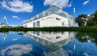 Fotografia przedstawia nowy pawilon muzeum. Budynek ma czystą, białą elewację i elementy przeszklone. Autorem zdjęcia jest J. Kordus.