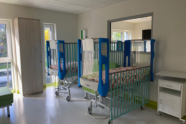 Na zdjęciu widać dwa łóżka szpitalne dla dzieci, z wysokimi, zdejmowanymi burtami i elektronicznym panelem sterowania. Zdjęcie pochodzi z archiwum beneficjenta.
