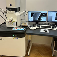 Na fotografii widoczne jest biurko, na którym stoi nowoczesny sprzęt badawczy. Z lewej strony znajduje się skomplikowane, niewielkie urządzenie, po prawej zaś komputer, dwa monitory z wyświetlonymi obrazami, a także panele sterownicze. Zdjęcie pochodzi z archiwum beneficjenta.