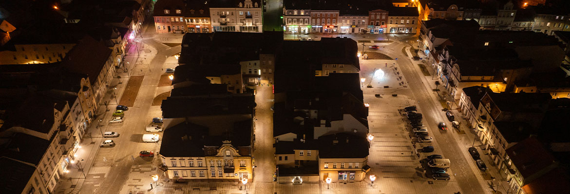 Fotografia z lotu ptaka, wykonana nocą, przedstawia szamotulski rynek. Widoczna jest płyta rynku, parkingi i budynki. Zdjęcie pochodzi z archiwum beneficjenta.