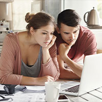 Na zdjęciu widzimy dwójkę młodych ludzi – kobietę i mężczyznę, którzy w skupieniu wpatrują się w ekran laptopa. Zdjęcie pochodzi z adobe stock.
