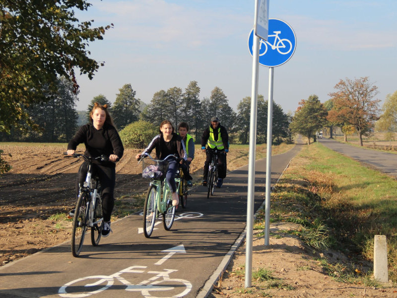 Fotografia przedstawia czwórkę rowerzystów poruszających się po ścieżce rowerowej. Zdjęcie pochodzi z archiwum beneficjenta.