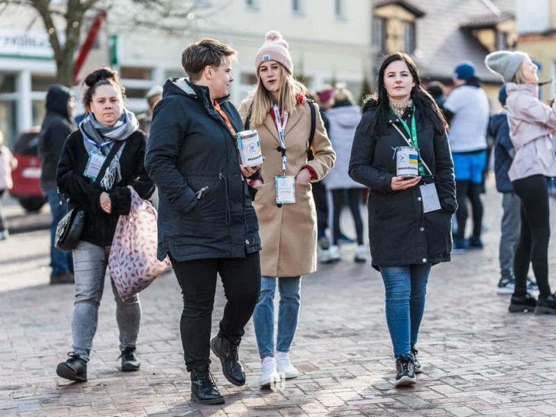 Zdjęcie przedstawia cztery kobiety, które zbierają pieniądze do puszek na ruchliwym deptaku. Fotografia pochodzi z archiwum beneficjenta.