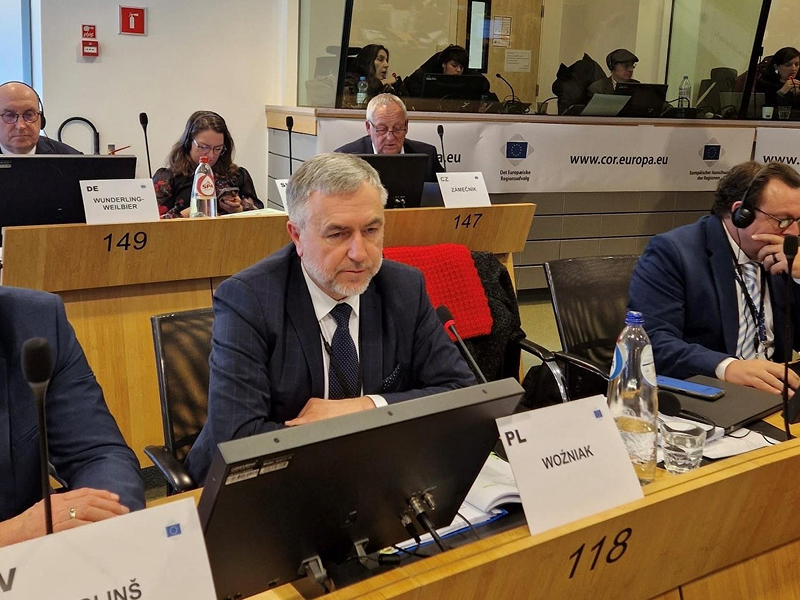 Na zdjęciu widoczny jest mężczyzna w garniturze i siwych włosach, siedzący w ławie, za monitorem. To marszałek województwa wielkopolskiego Marek Woźniak. Fotografia pochodzi z archiwum Urzędu Marszałkowskiego Województwa Wielkopolskiego.