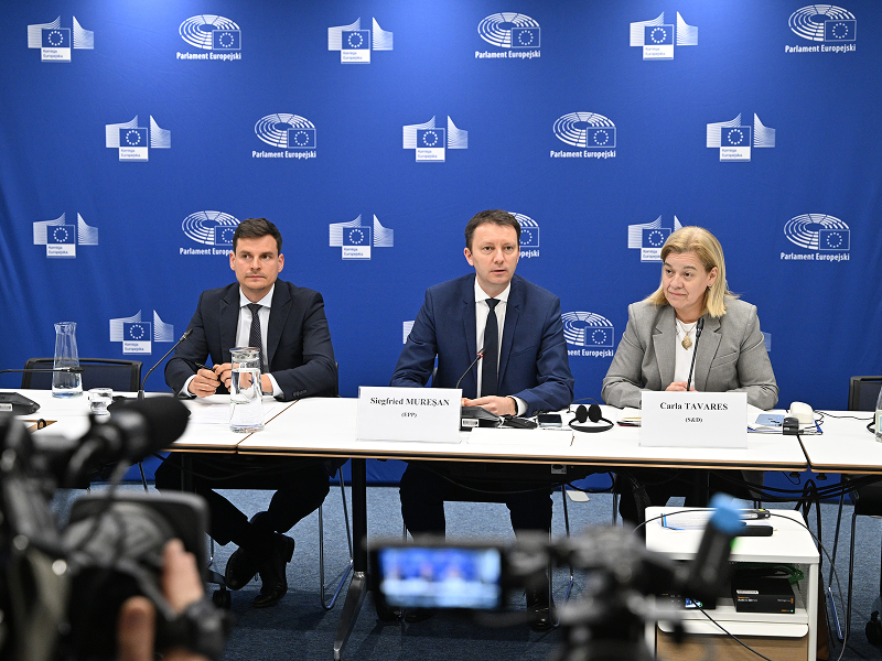 Ilustrację wykonano w trakcie konferencji prasowej. Pryz stoliku siedzą trzy osoby: dwóch mężczyzn w garniturach i kobieta o długich włosach. Za nimi znajduje się niebieska ścianka. Zdjęcie pochodzi z PAP MediaRoom M. Kmieciński.