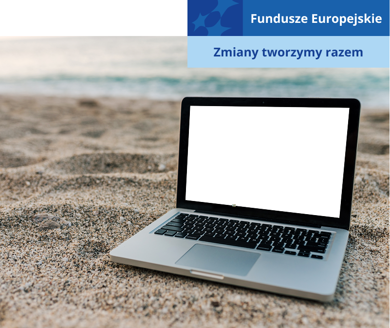 Fotografia przedstawia laptopa rozłożonego na piaszczystej plaży. W tle widoczna jest woda. Zdjęcie pochodzi z adobe stock.