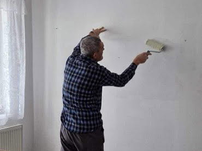 Na zdjęciu widoczny jest mężczyzna, który maluje ścianę na biało. Fotografia pochodzi z archiwum beneficjenta.