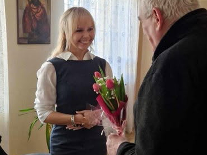 Fotografia przedstawia starszego mężczyznę wręczającego bukiet kwiatów uśmiechniętej kobiecie. Zdjęcie pochodzi z archiwum beneficjenta.